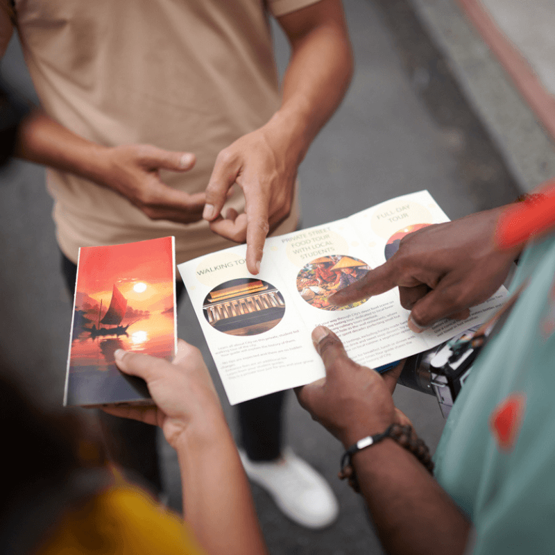 close up of group of three people holding and looking at an open brochure