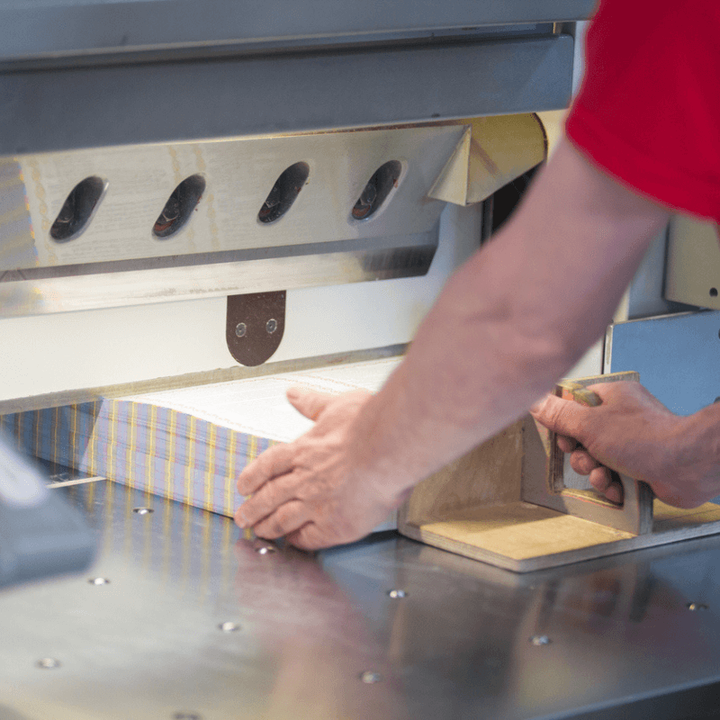 man aligning paper in a commercial print machine for bulk printing