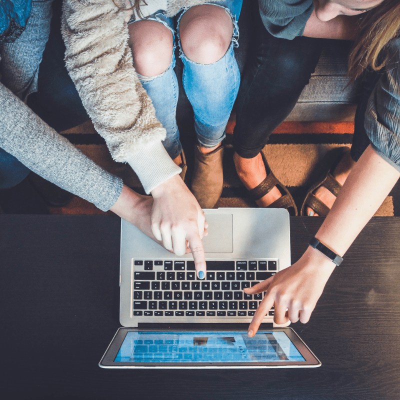 group of people pointing at a laptop