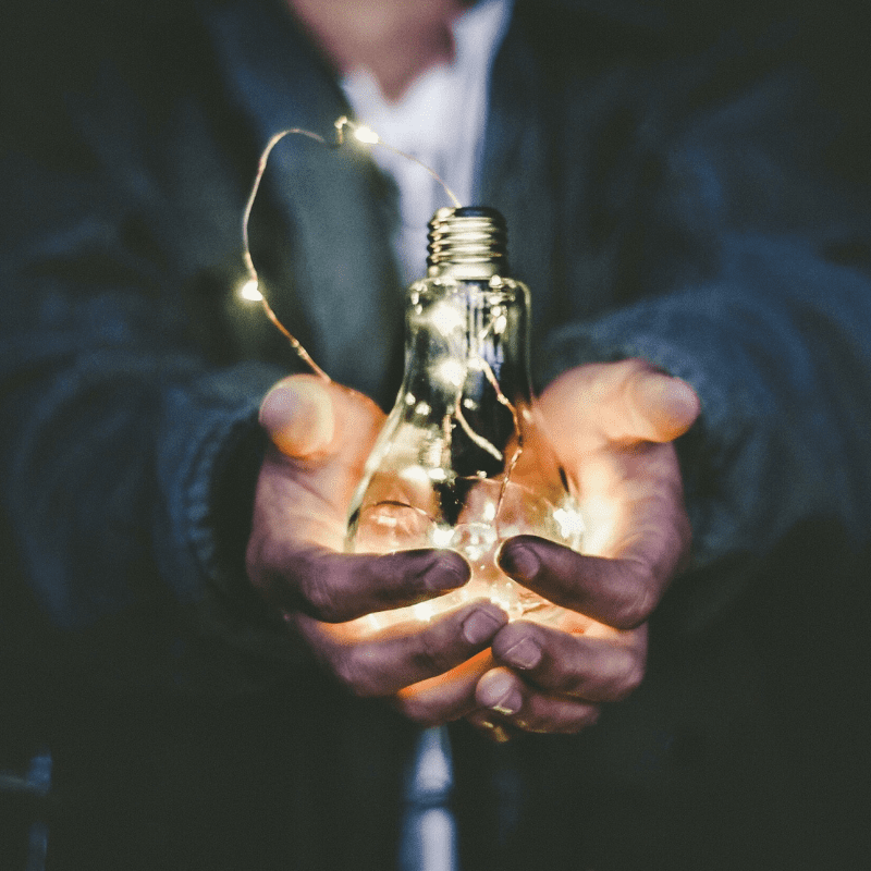 man holding a light bulb with fairy lights in his hands