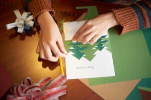 Making Christmas greeting card woman’s hands making a holiday greeting card