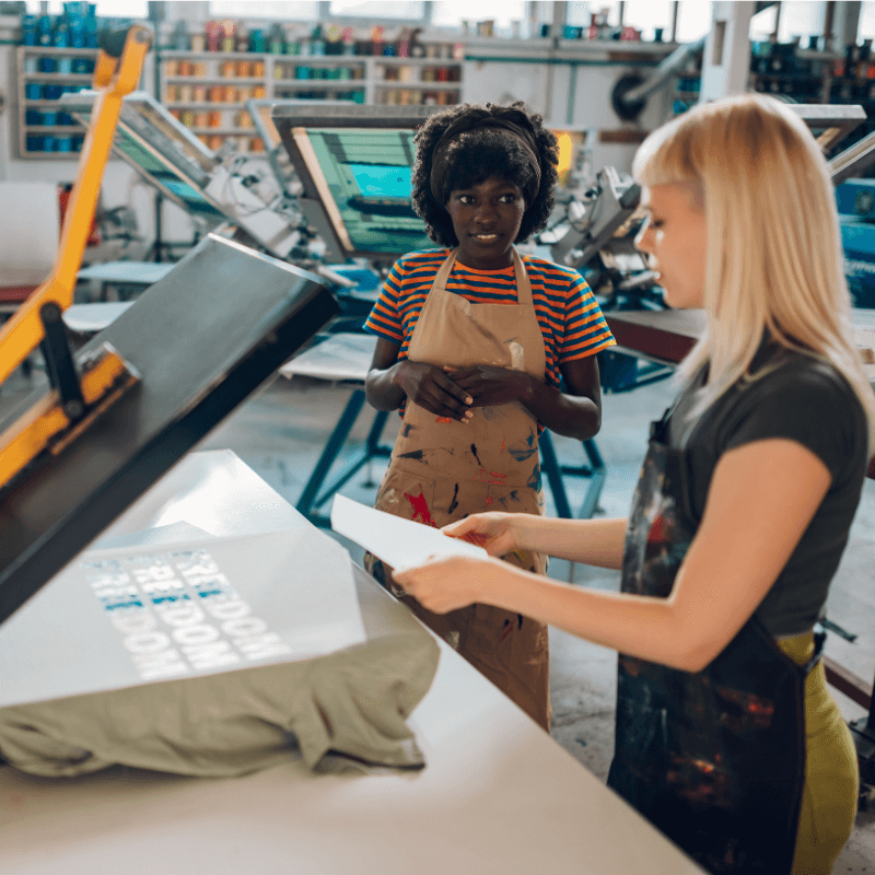 female-interracial-printing-shop-workers-working two professional printers working shop together