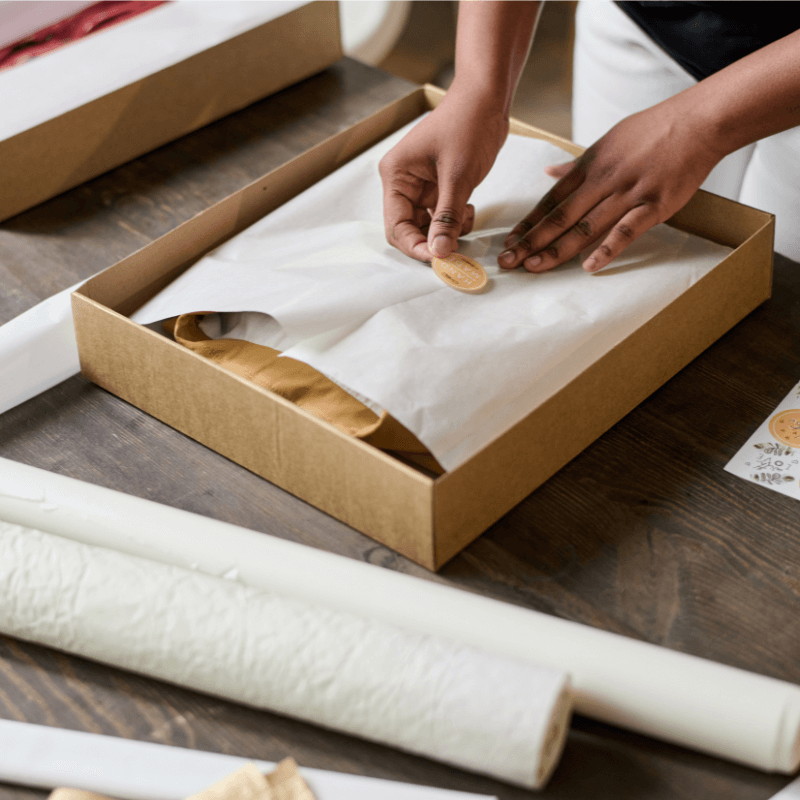 hands-of-young-black-woman-putting-sticker-on-top woman putting on custom stickers onto packaging