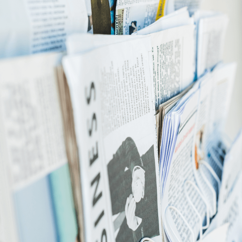 selective-focus-of-different-print-newspapers- Different print newspapers hanging on wall