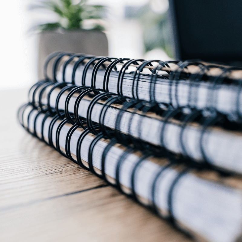 close-up-image-of-three-textbooks-and-potted-plant close-up look at spiral binding notebooks