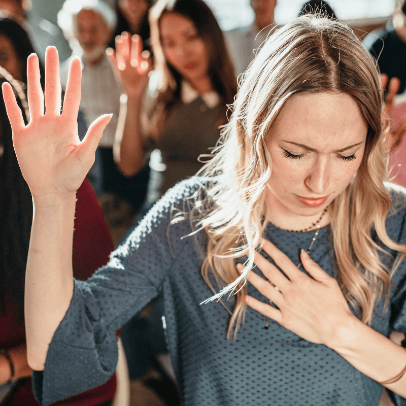 white woman raising her hand in church worship