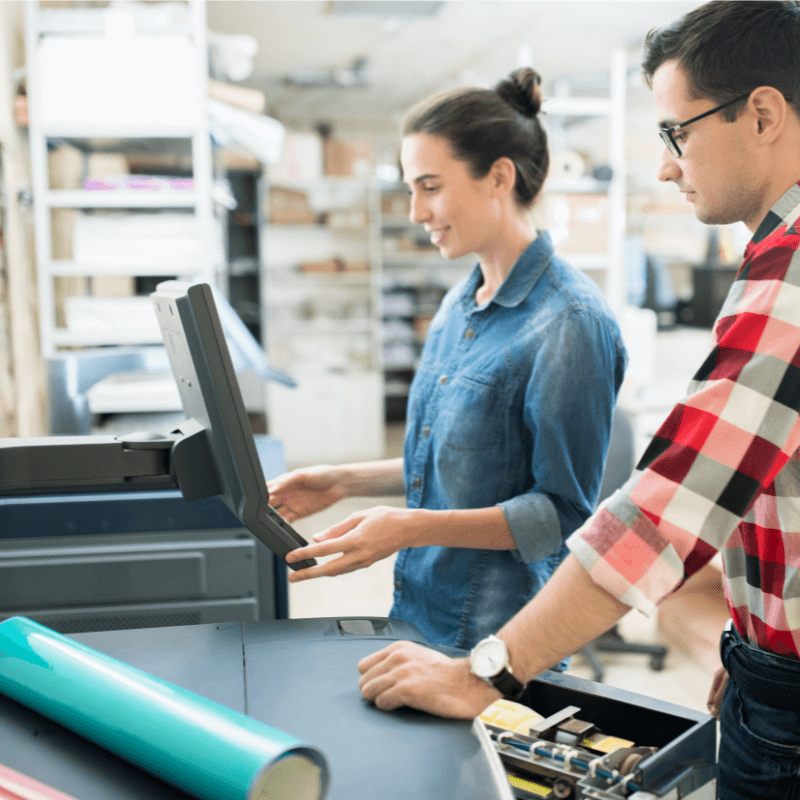 young male and female crafting print materials in a print shop