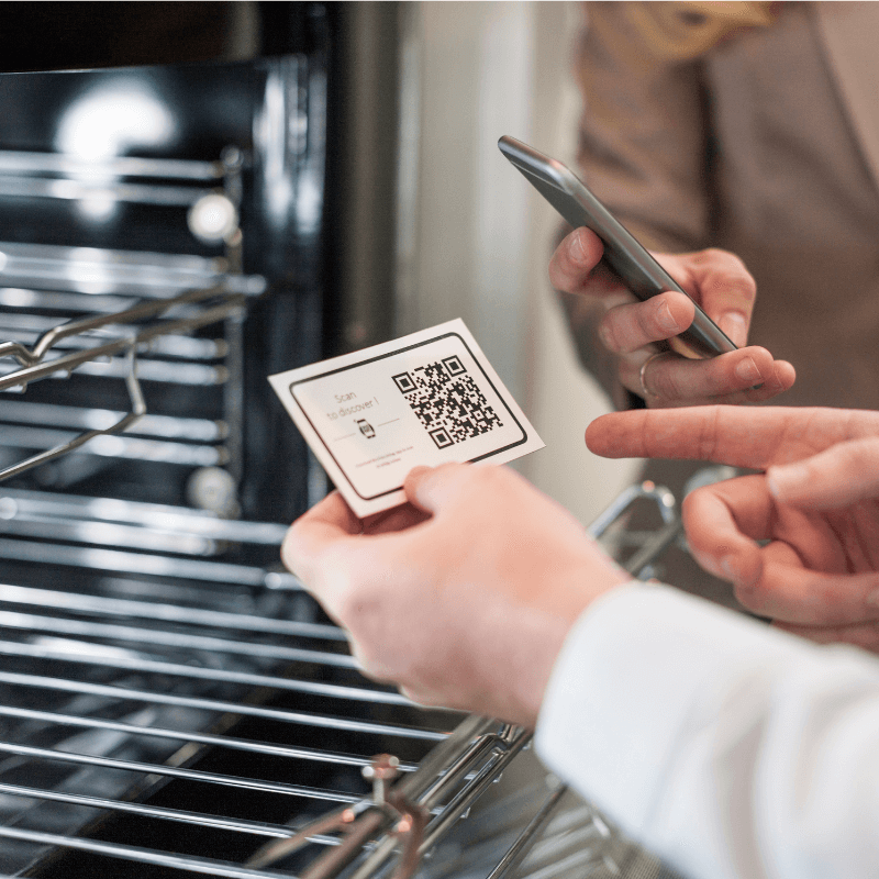 shop-assistant-amd-customer-at-oven-with-qr-code A shop assistant helping a customer with a QR code scan on a business card