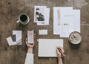 Woman holding a mobile phone mockup while writing on a notebook