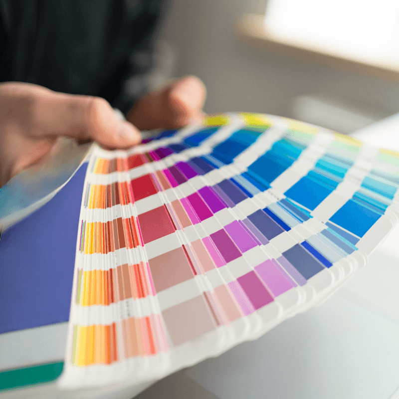 a-man-working-with-a-color-pallet-in-the-office A color swatch book or Pantone fan open on a desk