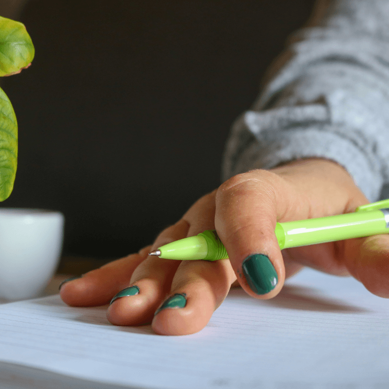 hand-with-green-pen-on-notepad A close-up of hands marking up a printed proof