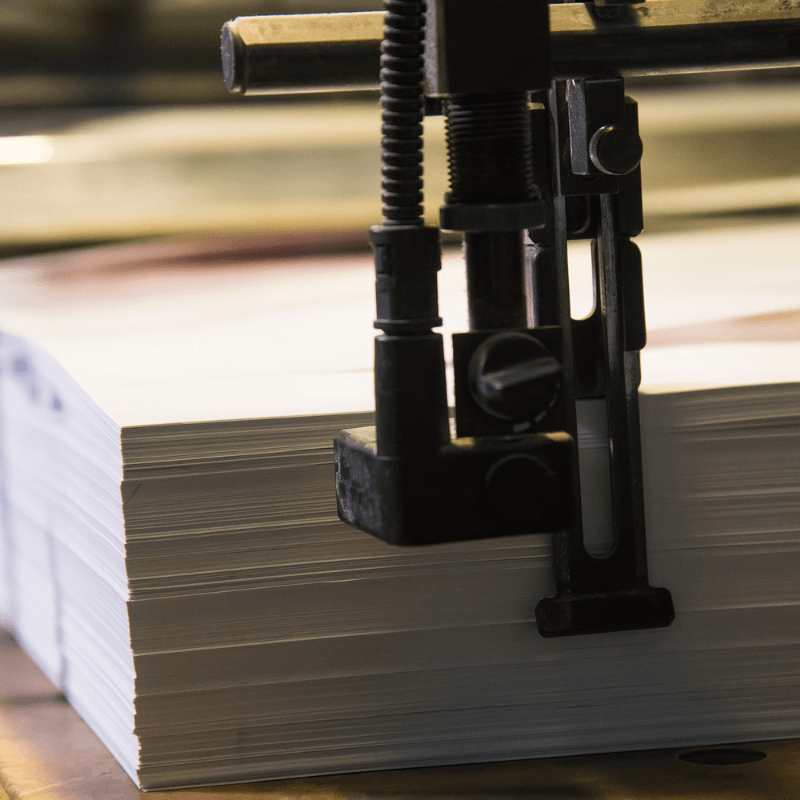 stack-of-printed-pages-in-a-printing-press Commercial printing press producing business marketing materials